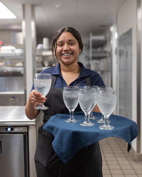 Staff member in kitchen with waters