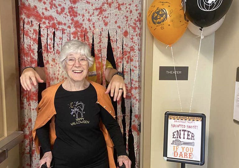 Resident at entrance to Haunted House with arms reaching over her shoulders