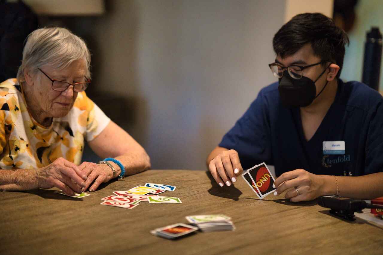 Two people sitting at a table playing the card game Uno.